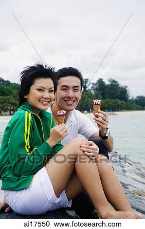 Couple sitting on breakwater, eating ice cream View Large Photo Image Stock Image - Couple sitting on breakwater, eating ice cream . Fotosearch