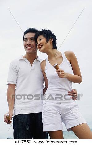 Couple standing, embracing, holding ice cream cones View Large Photo Image Stock Image - Couple standing, embracing, holding ice cream cones. Fotosearch