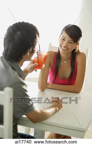 Couple toasting with drinks, sitting face to face View Large Photo Image Stock Image - Couple toasting with drinks, sitting face to face . Fotosearch