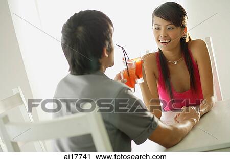 Couple toasting with drinks, sitting face to face, holding hands View Large Photo Image Stock Image - Couple toasting with drinks, sitting face to face, holding hands . Fotosearch
