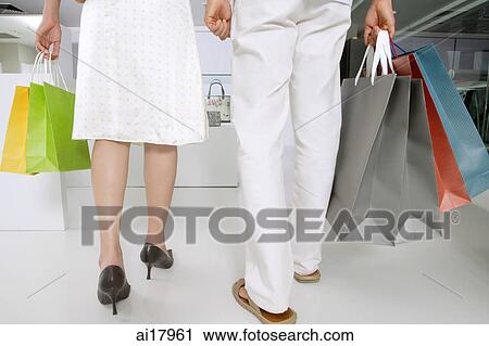Couple walking, carrying shopping bags, low section View Large Photo Image Stock Image - Couple walking, carrying shopping bags, low section . Fotosearch