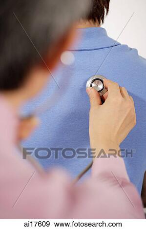 Doctor examining patient, listening to stethoscope View Large Photo Image Stock Photo - Doctor examining patient, listening to stethoscope . Fotosearch