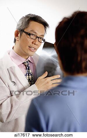 Doctor holding X-ray, consulting with patient View Large Photo Image Stock Photo - Doctor holding X-ray, consulting with patient . Fotosearch