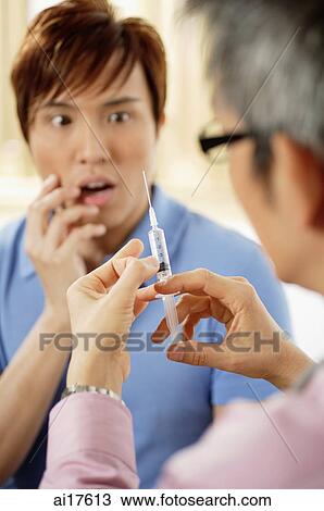 Doctor preparing syringe, patient cringing in background, selective focus View Large Photo Image Stock Image - Doctor preparing syringe, patient cringing in background, selective focus . Fotosearch