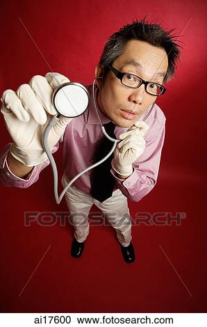 Stock Image - Doctor wearing mask, listening to stethoscope . Fotosearch