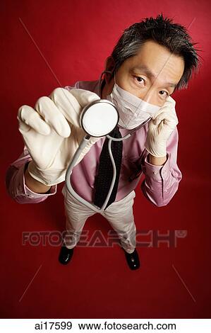 Doctor wearing mask, listening to stethoscope View Large Photo Image Stock Photo - Doctor wearing mask, listening to stethoscope. Fotosearch