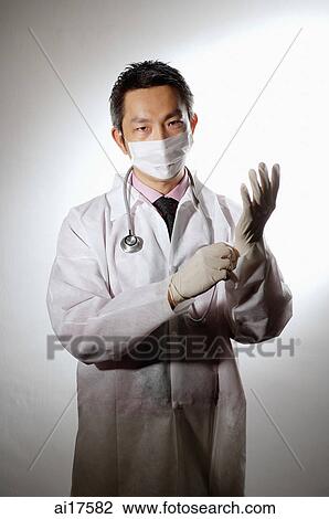 Doctor wearing mask, putting on gloves View Large Photo Image Stock Image - Doctor wearing mask, putting on gloves . Fotosearch