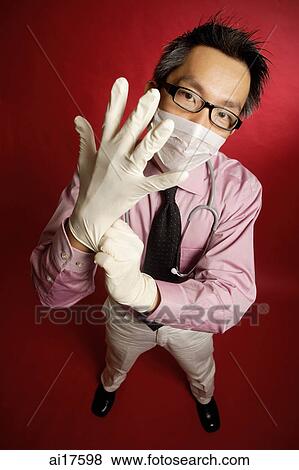 Doctor wearing mask, putting on gloves View Large Photo Image Stock Photo - Doctor wearing mask, putting on gloves . Fotosearch