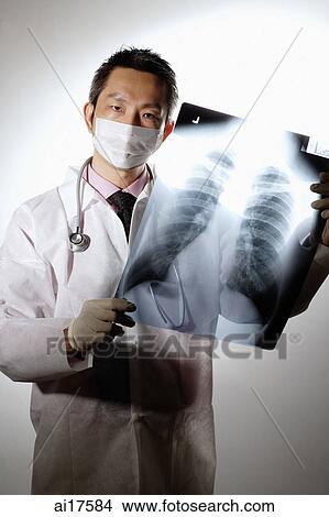 Doctor with face mask, holding X-Ray View Large Photo Image Picture - Doctor with face mask, holding X-Ray. Fotosearch