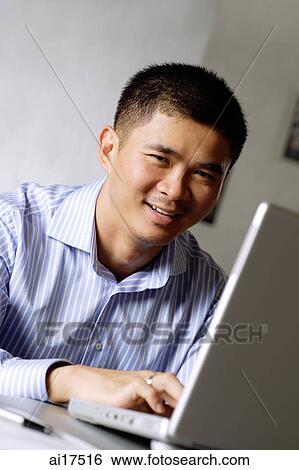 Executive using laptop, smiling at camera View Large Photo Image Stock Photograph - Executive using laptop, smiling at camera . Fotosearch