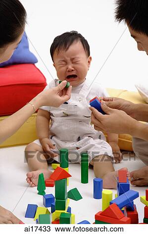 Family with one child, baby crying, parents trying to pacify him with toys View Large Photo Image Stock Image - Family with one child, baby crying, parents trying to pacify him with toys . Fotosearch