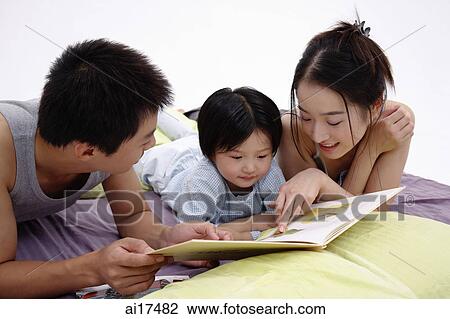 Family with one child lying on bed, reading book View Large Photo Image Stock Image - Family with one child lying on bed, reading book . Fotosearch