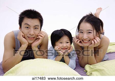 Family with one child, lying on bed, hand on chin View Large Photo Image Stock Image - Family with one child, lying on bed, hand on chin . Fotosearch