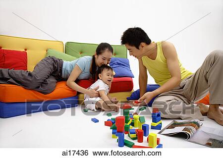 Family with one child, sitting in living room, playing with wooden toy blocks View Large Photo Image Stock Photograph - Family with one child, sitting in living room, playing with wooden toy blocks . Fotosearch