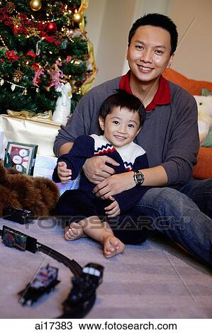 Father and son smiling at camera, Christmas tree behind them View Large Photo Image Stock Image - Father and son smiling at camera, Christmas tree behind them . Fotosearch
