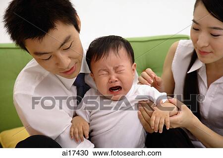 Father holding crying baby boy, mother sitting next to them View Large Photo Image Stock Image - Father holding crying baby boy, mother sitting next to them . Fotosearch