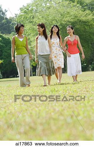 Four young women walking side by side in park View Large Photo Image Stock Image - Four young women walking side by side in park . Fotosearch
