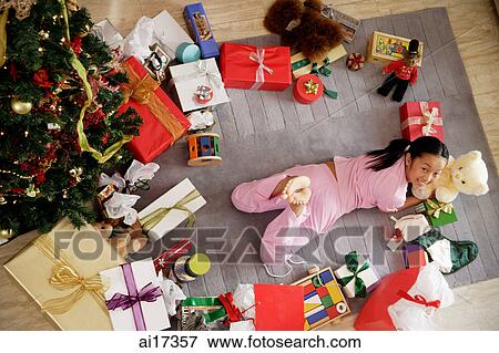 Girl lying on floor, surrounded by gifts, looking at camera View Large Photo Image Stock Photo - Girl lying on floor, surrounded by gifts, looking at camera . Fotosearch