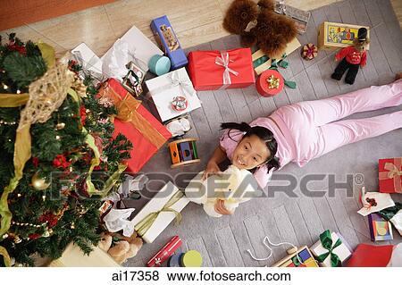 Girl lying on floor, surrounded by presents, holding teddy bear, looking at camera View Large Photo Image Stock Photo - Girl lying on floor, surrounded by presents, holding teddy bear, looking at camera . Fotosearch