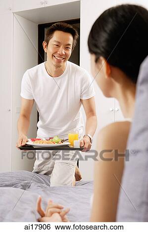 Man bringing woman breakfast in bed View Large Photo Image Stock Photograph - Man bringing woman breakfast in bed . Fotosearch