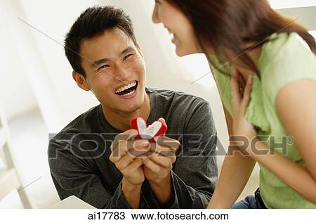 Man crouching next to woman presenting her with ring in box View Large Photo Image Stock Image - Man crouching next to woman presenting her with ring in box . Fotosearch