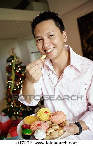 Man holding a plate of food, eating a cookie View Large Photo Image Stock Image - Man holding a plate of food, eating a cookie. Fotosearch
