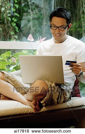 Man holding credit card and using laptop View Large Photo Image Stock Photo - Man holding credit card and using laptop. Fotosearch