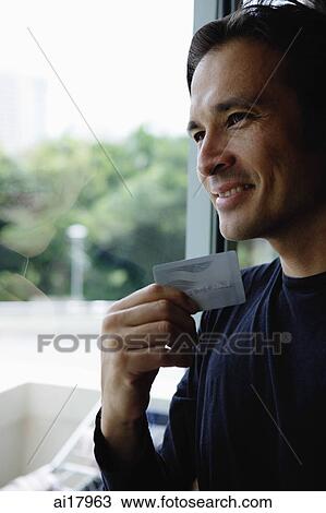Man holding credit card, smiling, looking out the window View Large Photo Image Stock Image - Man holding credit card, smiling, looking out the window . Fotosearch