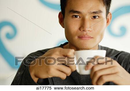 Stock Photography - Man holding cup, looking at camera. Fotosearch