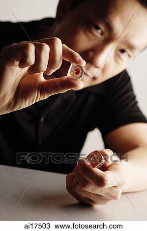 Stock Image - Man holding dice. Fotosearch