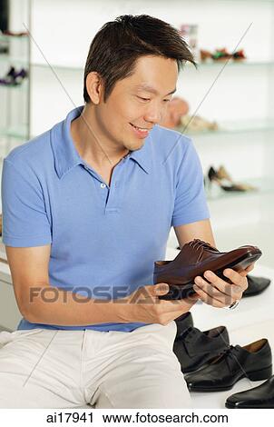 Stock Image - Man holding shoe in shoe shop. Fotosearch