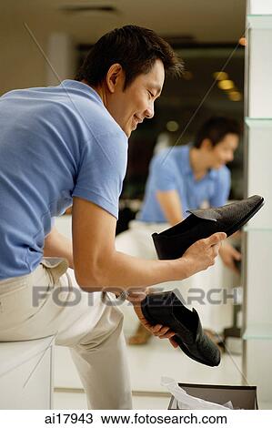 Man in shoe shop, looking at shoes View Large Photo Image Stock Image - Man in shoe shop, looking at shoes . Fotosearch