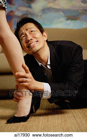 Stock Image - Man lying on floor, holding onto womans leg. Fotosearch