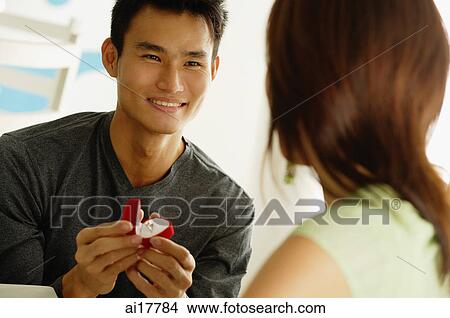Man proposing to woman, holding ring box View Large Photo Image Picture - Man proposing to woman, holding ring box . Fotosearch