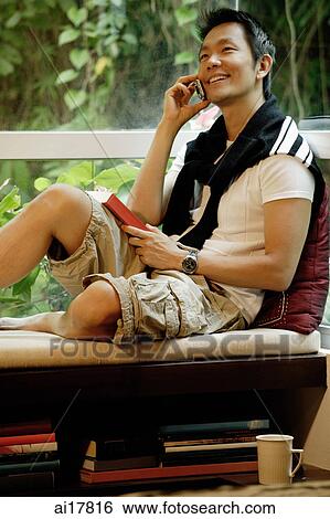 Man sitting at home, using mobile phone View Large Photo Image Stock Photograph - Man sitting at home, using mobile phone . Fotosearch
