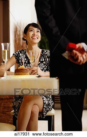 Man standing, holding ring box behind his back, facing seated woman View Large Photo Image Stock Image - Man standing, holding ring box behind his back, facing seated woman. Fotosearch