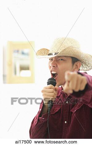 Man wearing hat, holding mike, singing and pointing at camera View Large Photo Image Stock Image - Man wearing hat, holding mike, singing and pointing at camera . Fotosearch