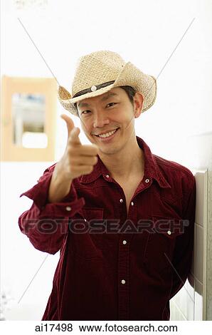 Stock Photo - Man wearing hat, pointing finger, smiling at camera . Fotosearch