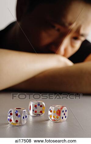 Three dice on a table, man looking at them frowning View Large Photo Image Stock Photo - Three dice on a table, man looking at them frowning . Fotosearch
