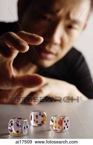 Three dice on a table, man reaching for them View Large Photo Image Stock Photo - Three dice on a table, man reaching for them. Fotosearch