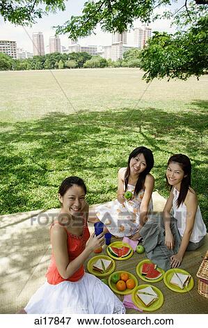 Three women having a picnic in park, smiling at camera View Large Photo Image Stock Photo - Three women having a picnic in park, smiling at camera . Fotosearch