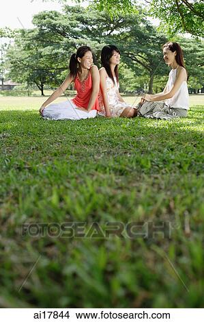 Picture - Three women sitting on grass in park. Fotosearch