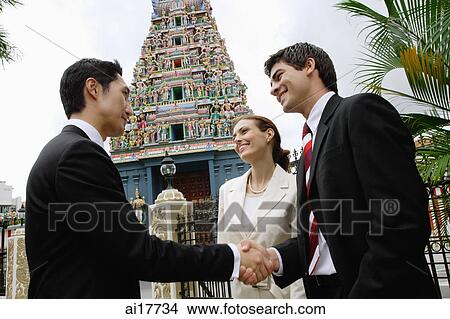 Two businessmen and one businesswoman in front of Hindu temple, looking at camera View Large Photo Image Picture - Two businessmen and one businesswoman in front of Hindu temple, looking at camera. Fotosearch