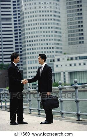 Two businessmen shaking hands, river and buildings in the background View Large Photo Image Stock Image - Two businessmen shaking hands, river and buildings in the background . Fotosearch