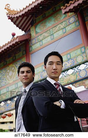 Two businessmen standing, looking at camera, temple gate in the background View Large Photo Image Stock Photo - Two businessmen standing, looking at camera, temple gate in the background. Fotosearch