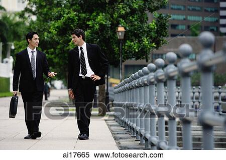 Two businessmen walking and talking View Large Photo Image Stock Photography - Two businessmen walking and talking. Fotosearch