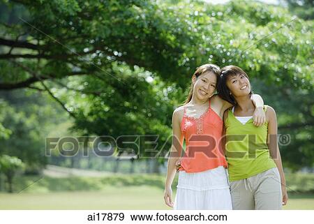 Two young women, arms around each other, smiling at camera View Large Photo Image Stock Photo - Two young women, arms around each other, smiling at camera. Fotosearch