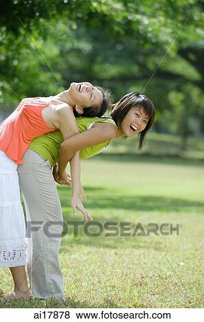 Two young women, back to back, one bending forward View Large Photo Image Stock Photo - Two young women, back to back, one bending forward . Fotosearch