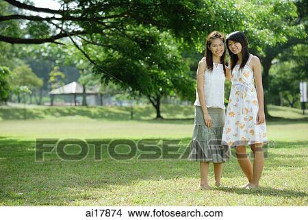 Two young women standing side by side, smiling at camera View Large Photo Image Picture - Two young women standing side by side, smiling at camera . Fotosearch