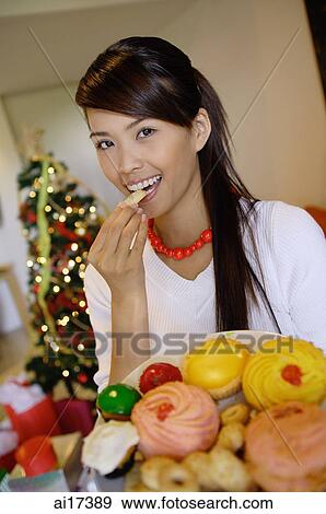 Woman eating a cookie, holding plate of food View Large Photo Image Stock Photo - Woman eating a cookie, holding plate of food. Fotosearch